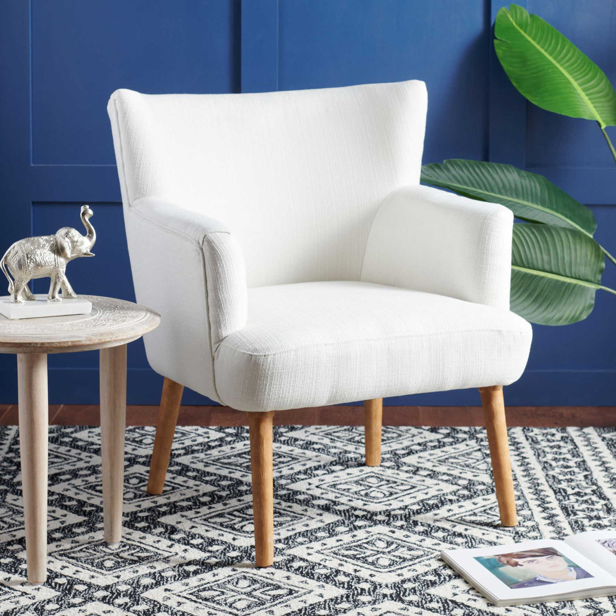 White upholstered accent chair brightens the space with soft curves and warm wood legs
