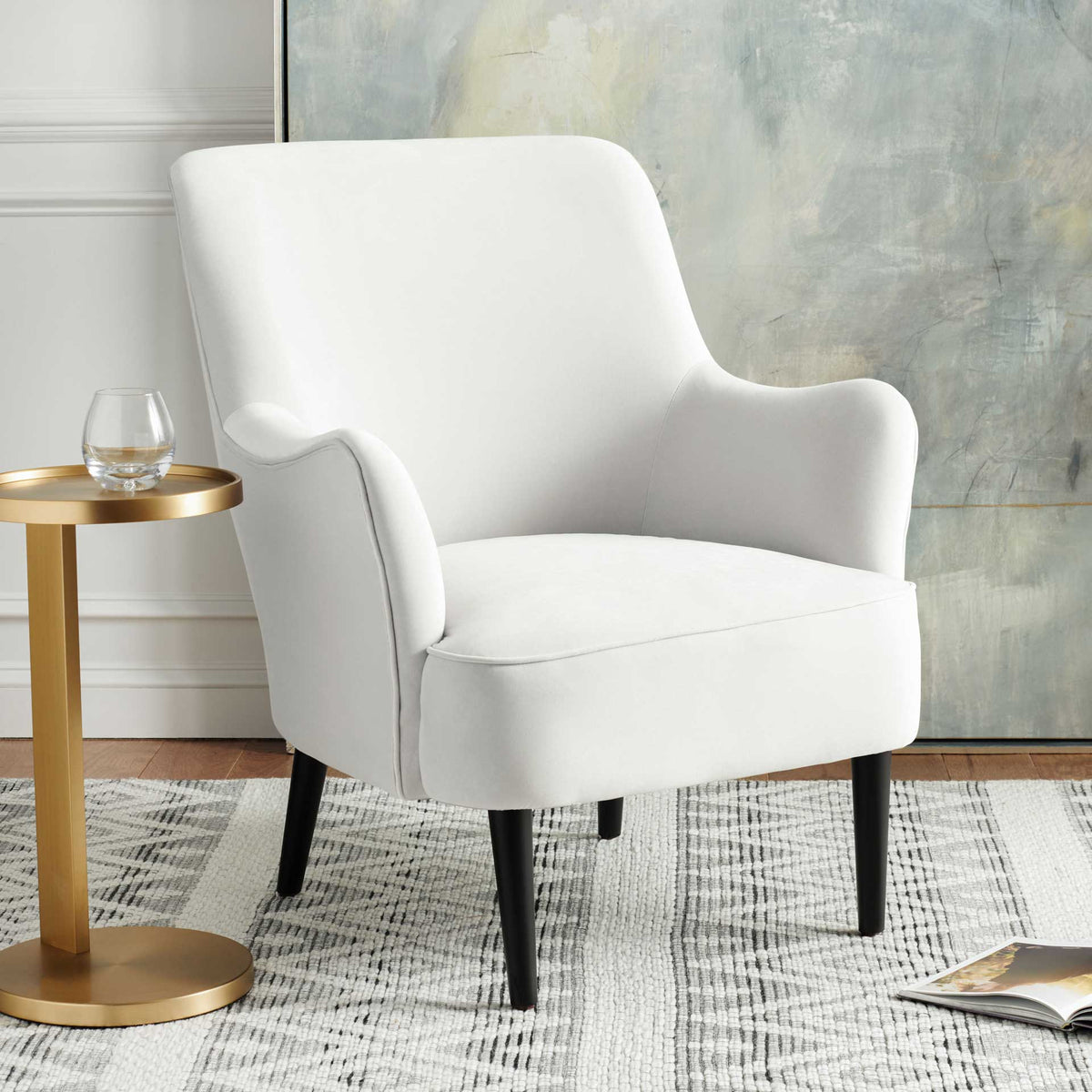 A white velvet chair pairs an inviting cushioned seat and sculpted arms with sleek black legs
