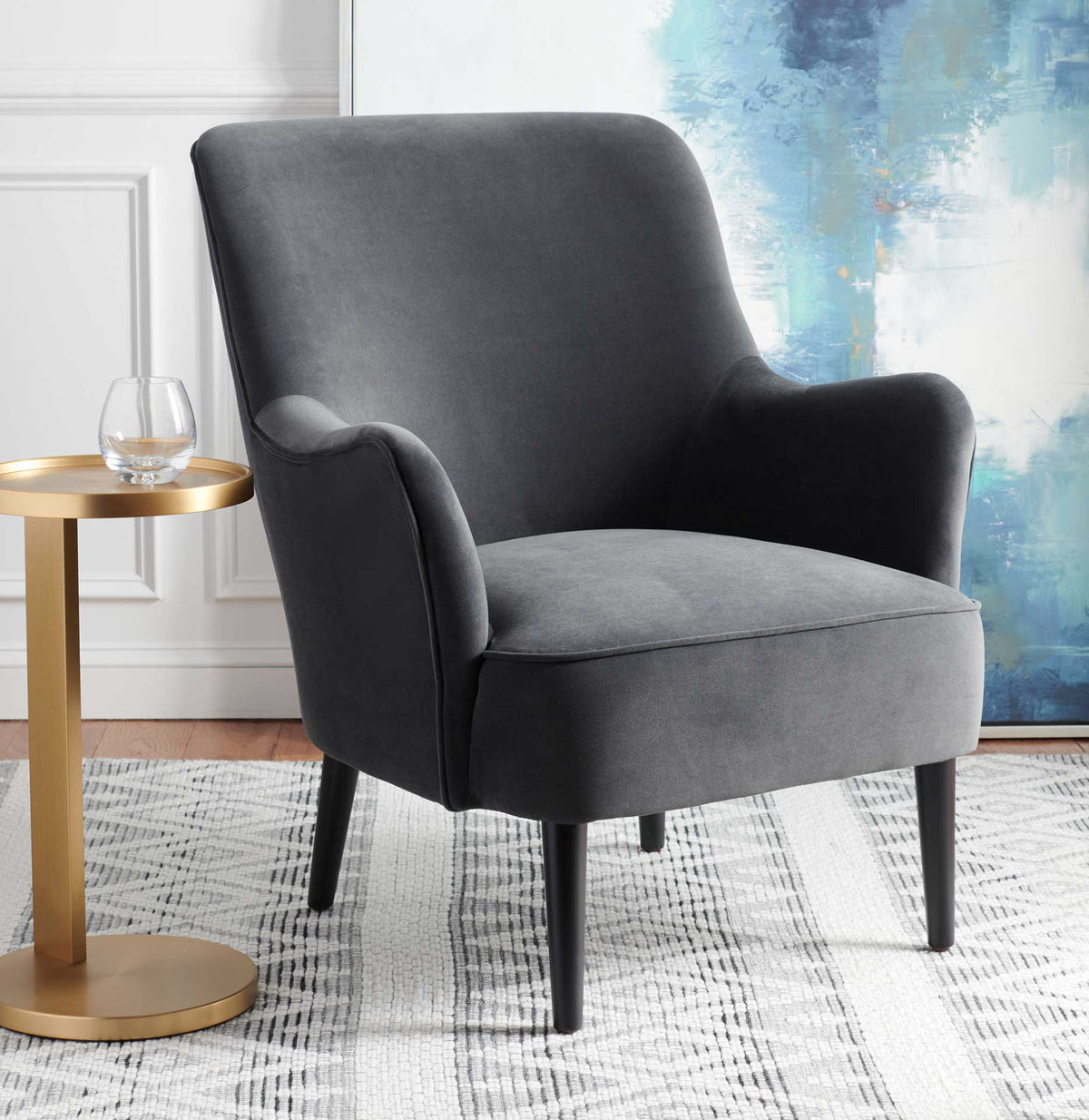A cozy black velvet chair with a roomy seat and sculpted arms rests on sleek tapered legs