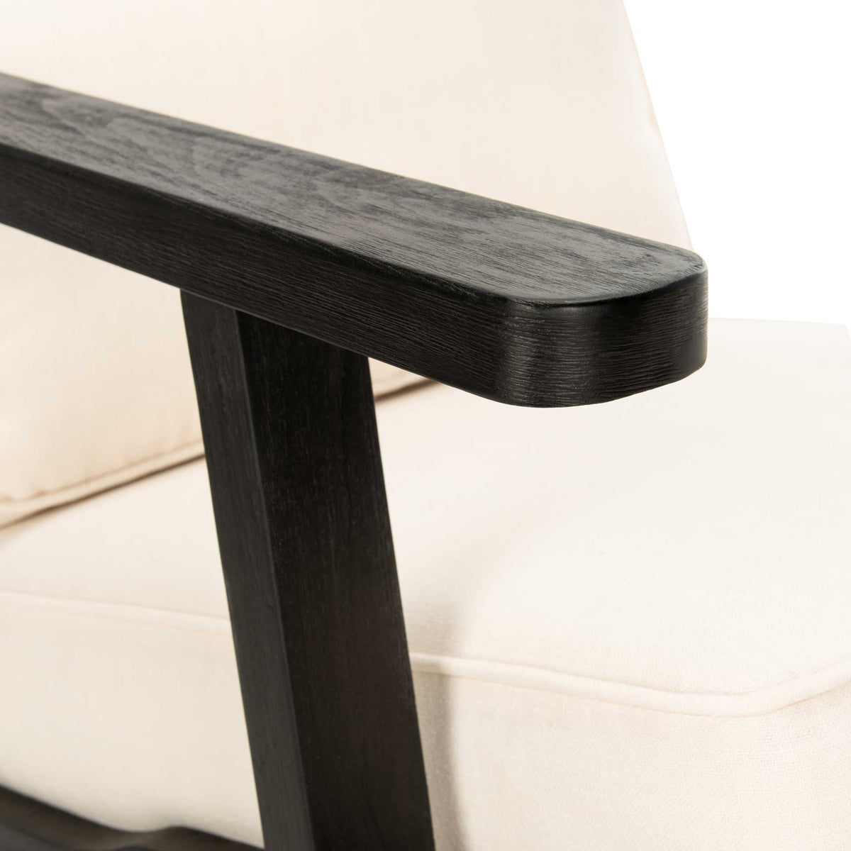A smoothly rounded black oak armrest contrasts with the pale linen upholstery