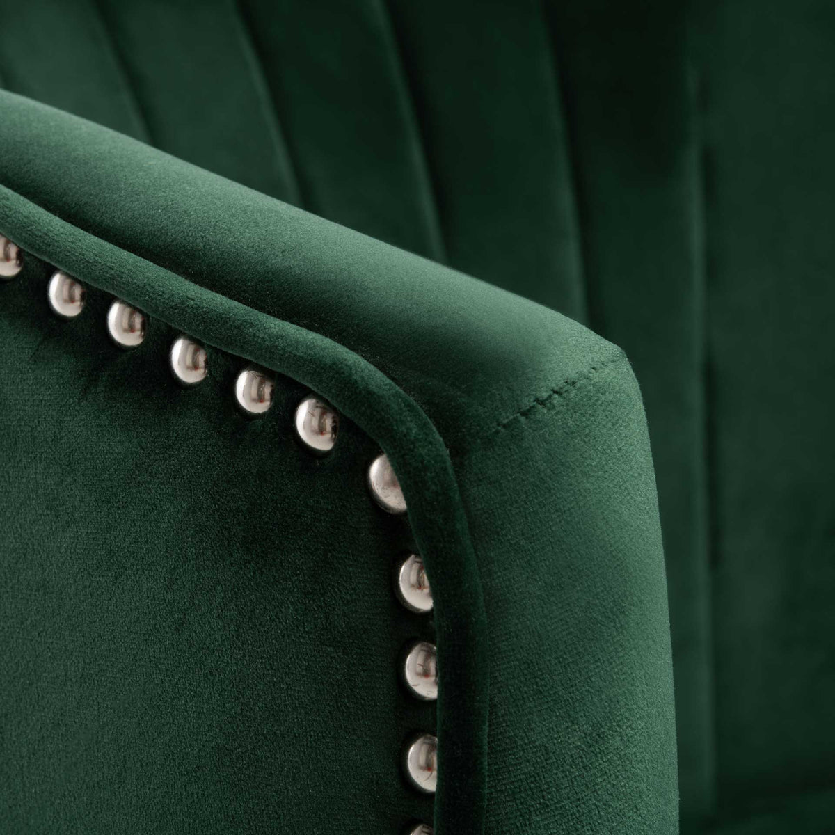 Silver-toned nailheads trace the softly padded edge of the forest green velvet wing.