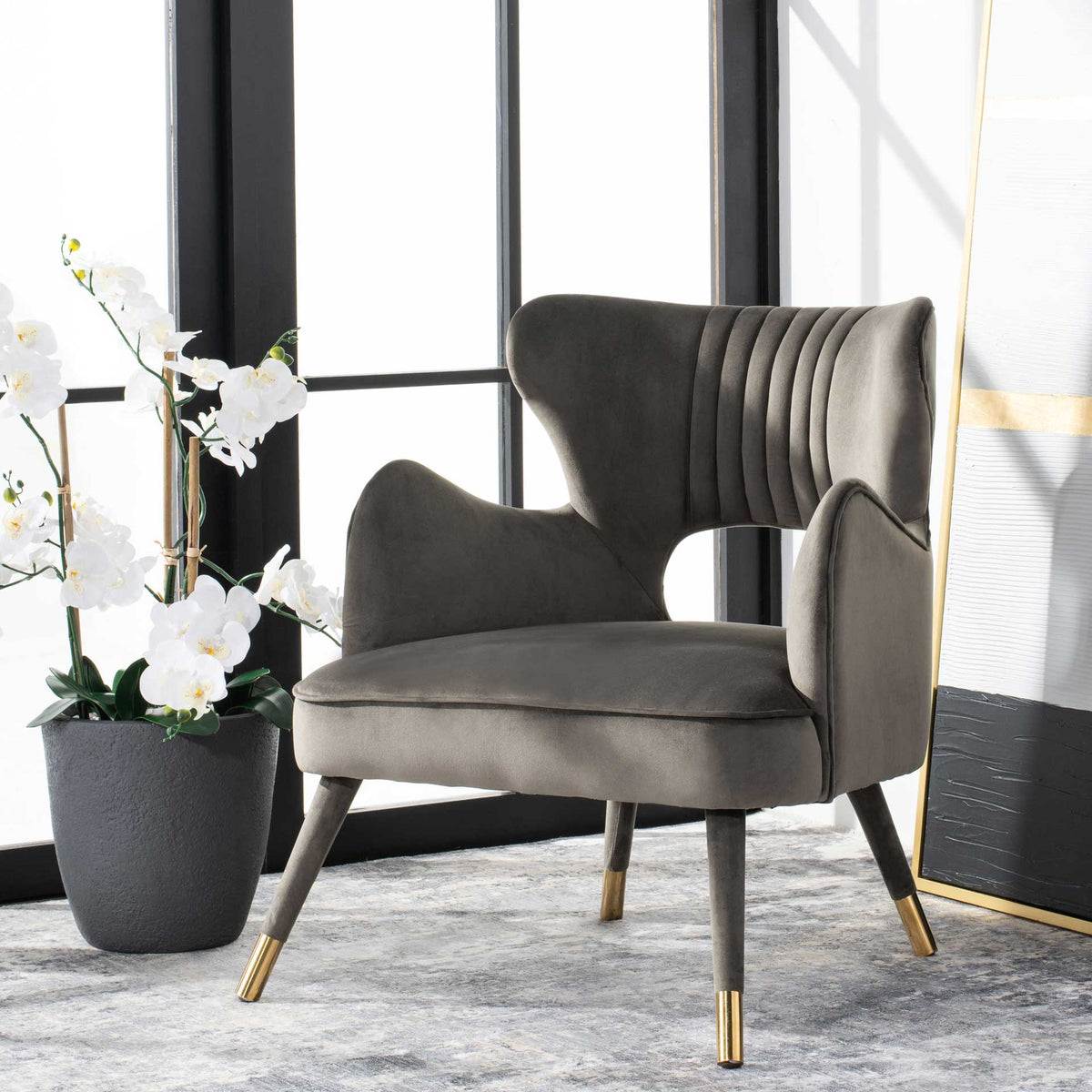 Plush shale gray velvet and gold-tipped legs add understated glam to a sculpted accent chair