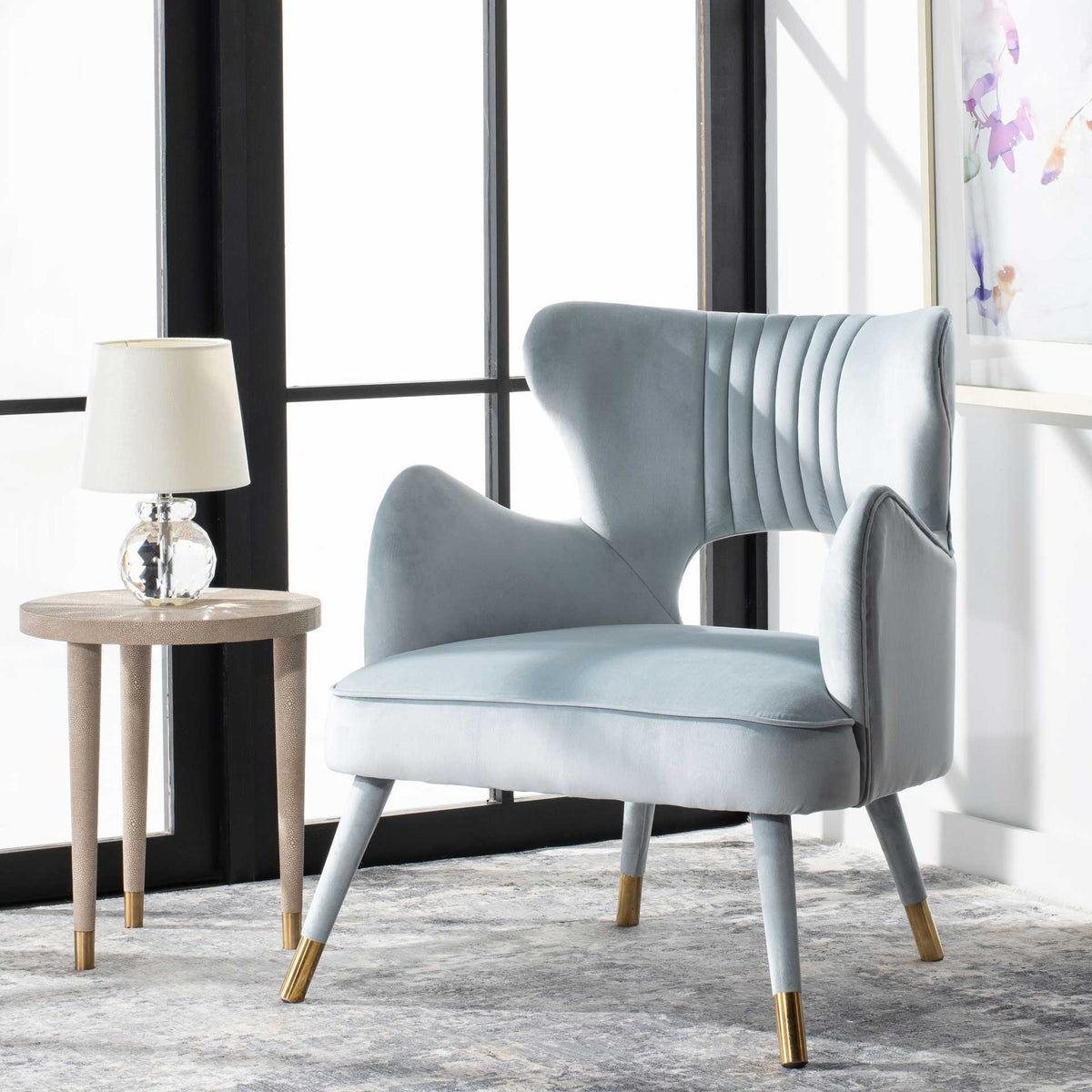 Light blue velvet and gold-capped legs brighten this curved wingback chair with a cutout back