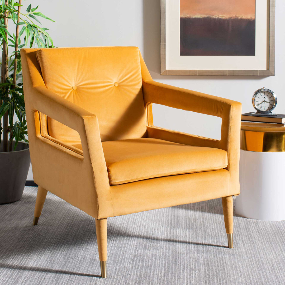 Marigold velvet upholstery, button tufting and open arms give this accent chair warm retro flair.