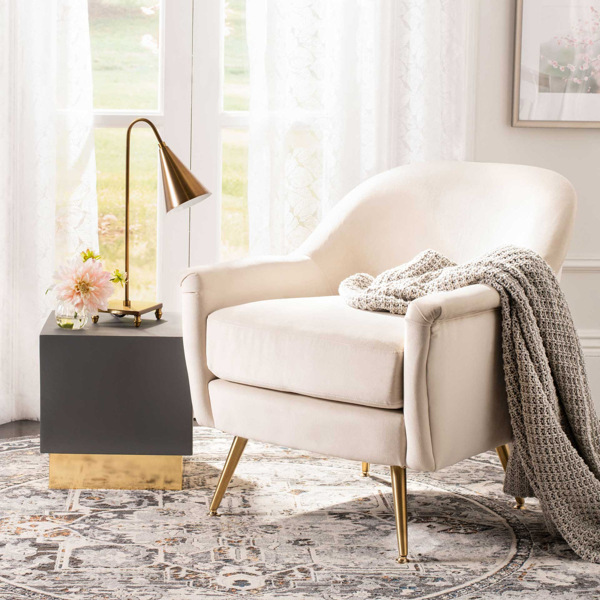Ivory velvet and brass-tone legs make this cushioned chair a serene addition to a cozy room