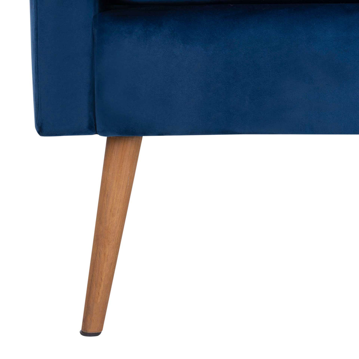 A tapered natural oak leg grounds the navy velvet chair in mid-century style