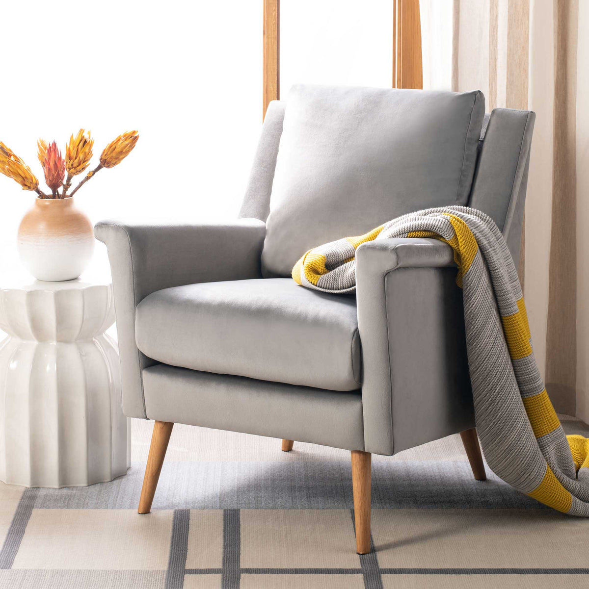 Stone gray velvet armchair offers a cozy seat with soft cushions and natural oak legs