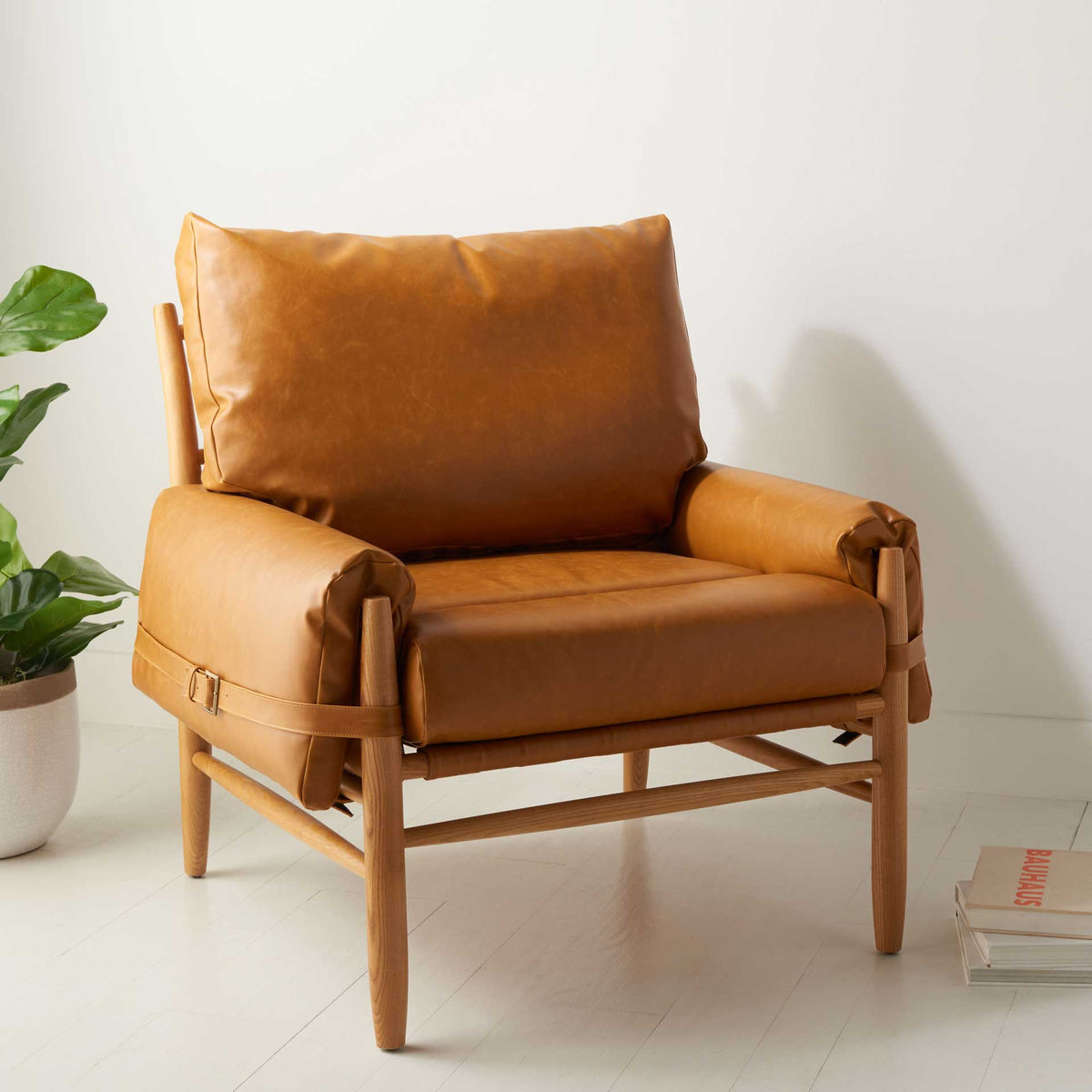 Plush caramel cushions and rounded arms rest on a slim oak frame for relaxed mid-century style.