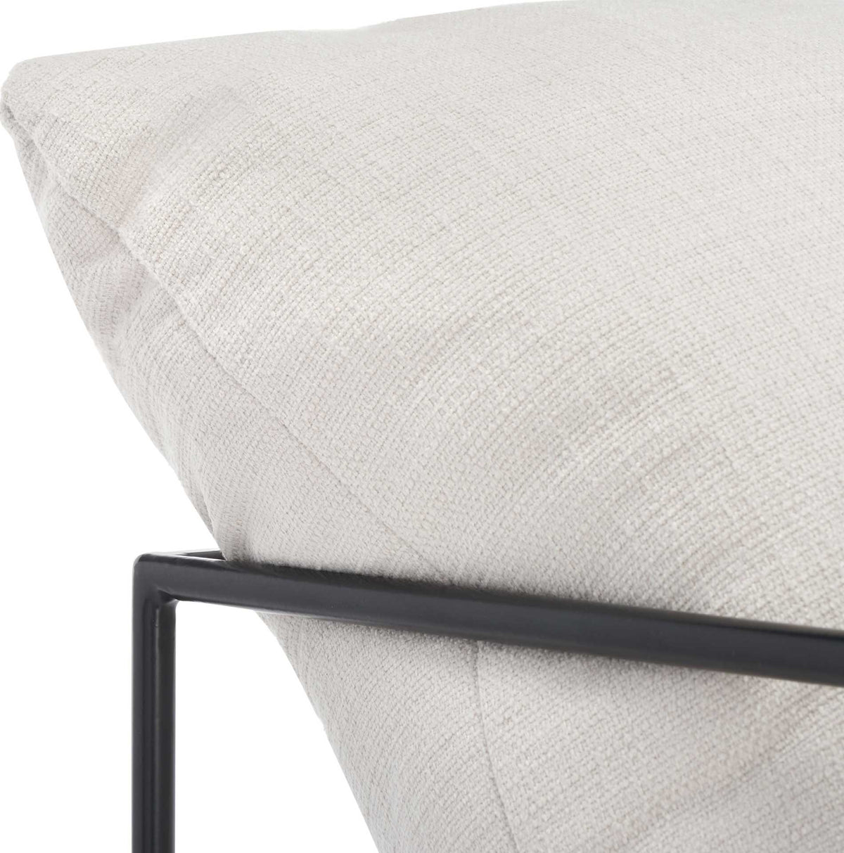 Subtle ivory linen texture meets a slender black iron arm along the cushioned back.