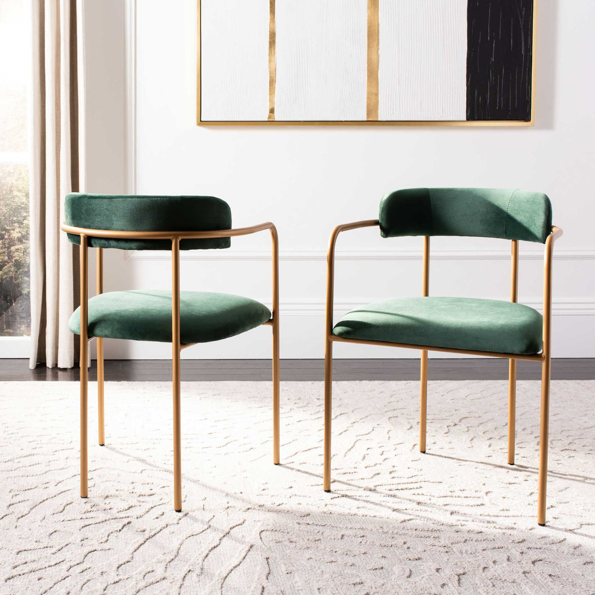 Two green velvet side chairs add jewel-toned color and open gold lines to a bright interior