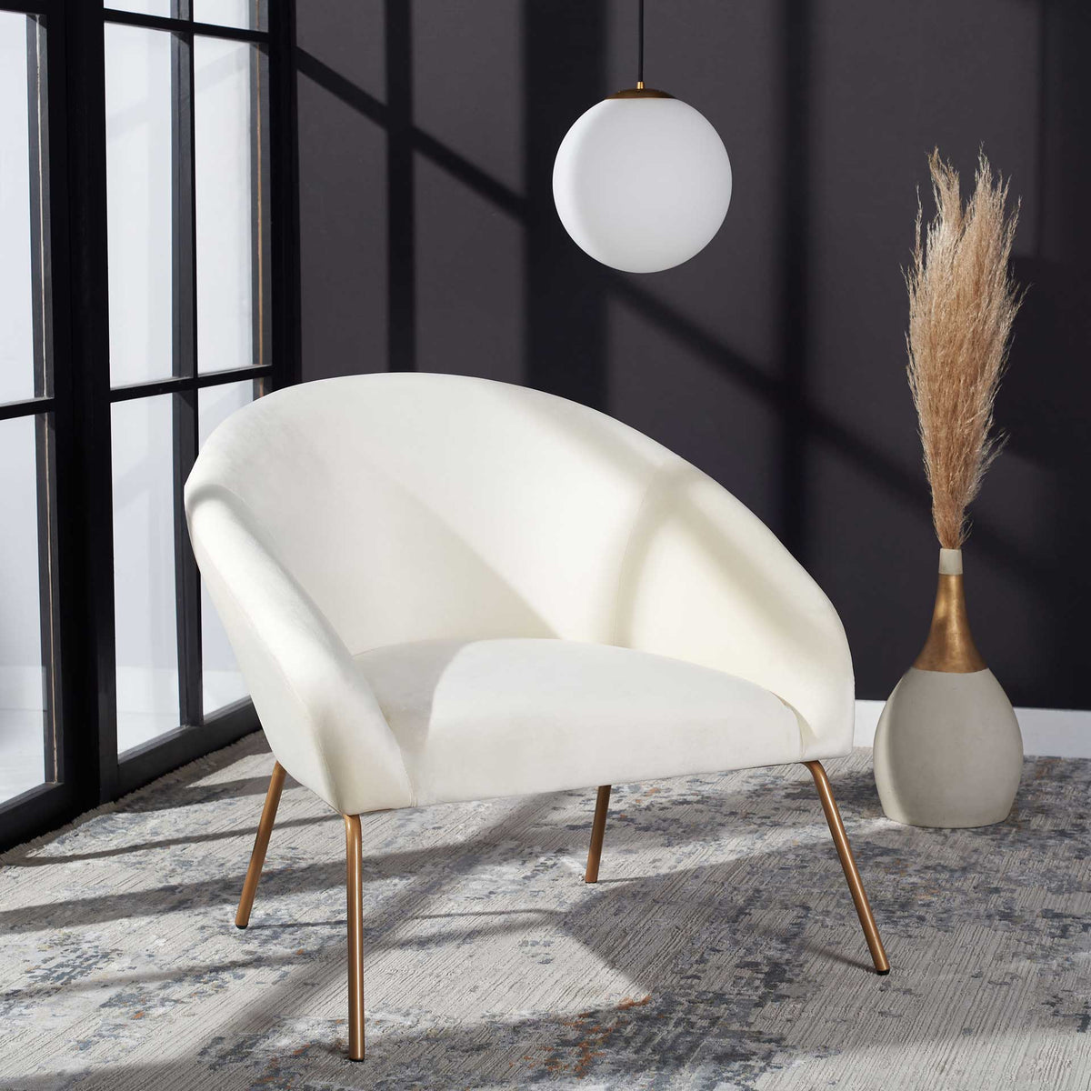 Cream velvet and slender gold legs add airy elegance to a softly curved accent chair