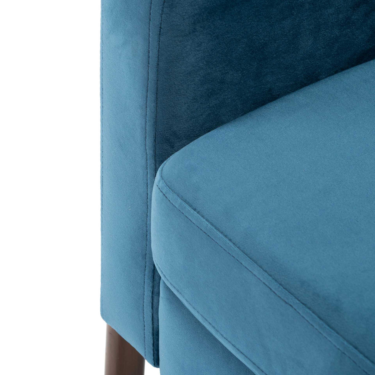 Plush blue velvet seat cushion features clean piping beside a padded, tailored arm