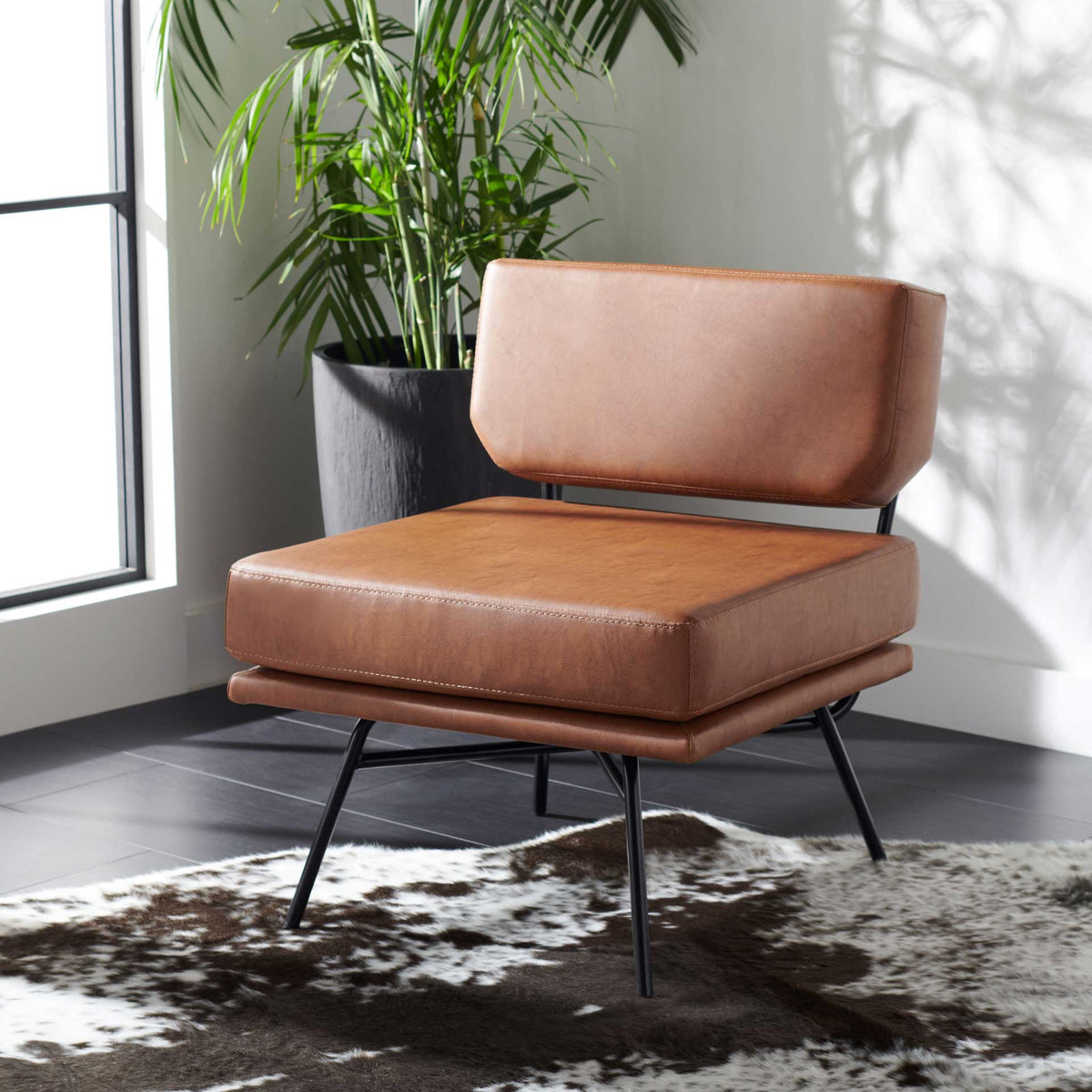 Plush cognac cushions and splayed black metal legs add inviting midcentury style to a living space.