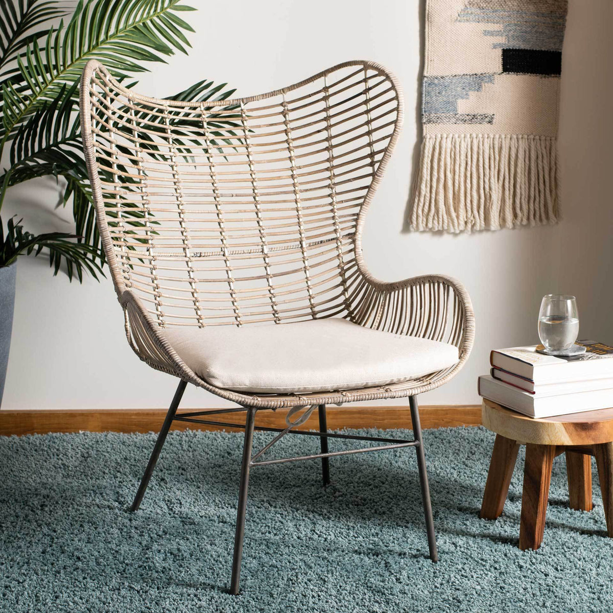 A sculptural rattan wingback and white cushioned seat add natural texture to a cozy living space