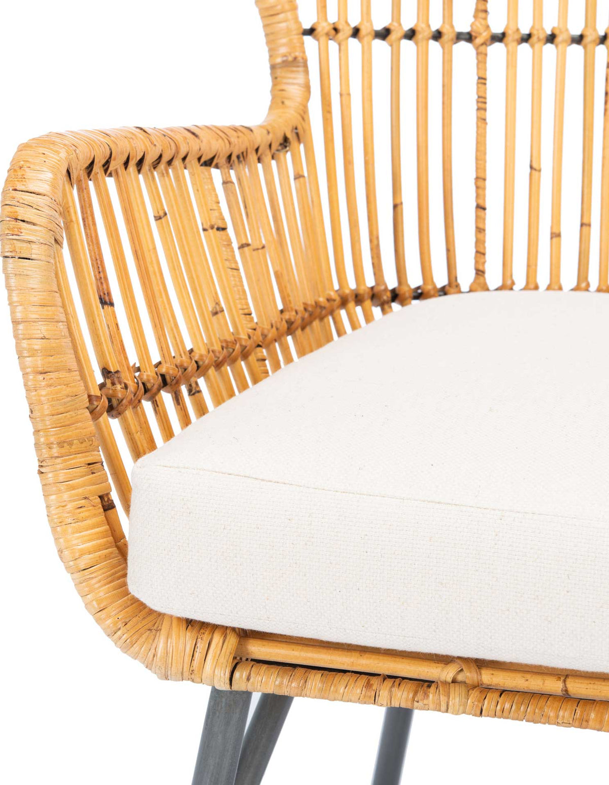 The plush white cushion contrasts with a curved natural rattan arm and closely spaced spindles