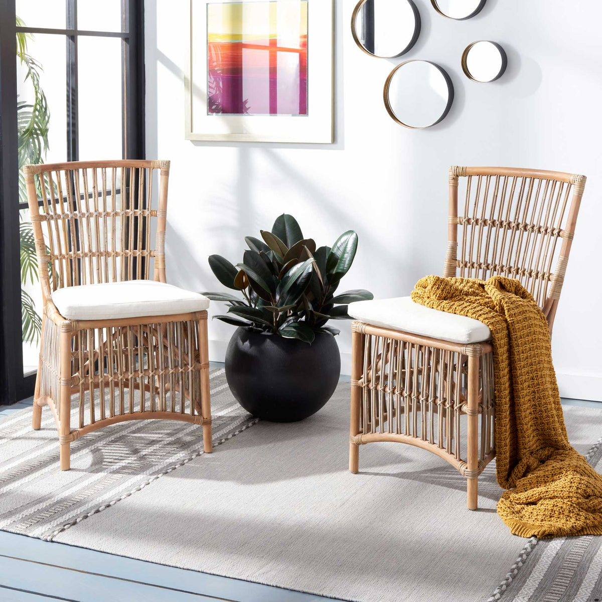 Two gray-washed rattan chairs with white cushions lend a relaxed coastal touch