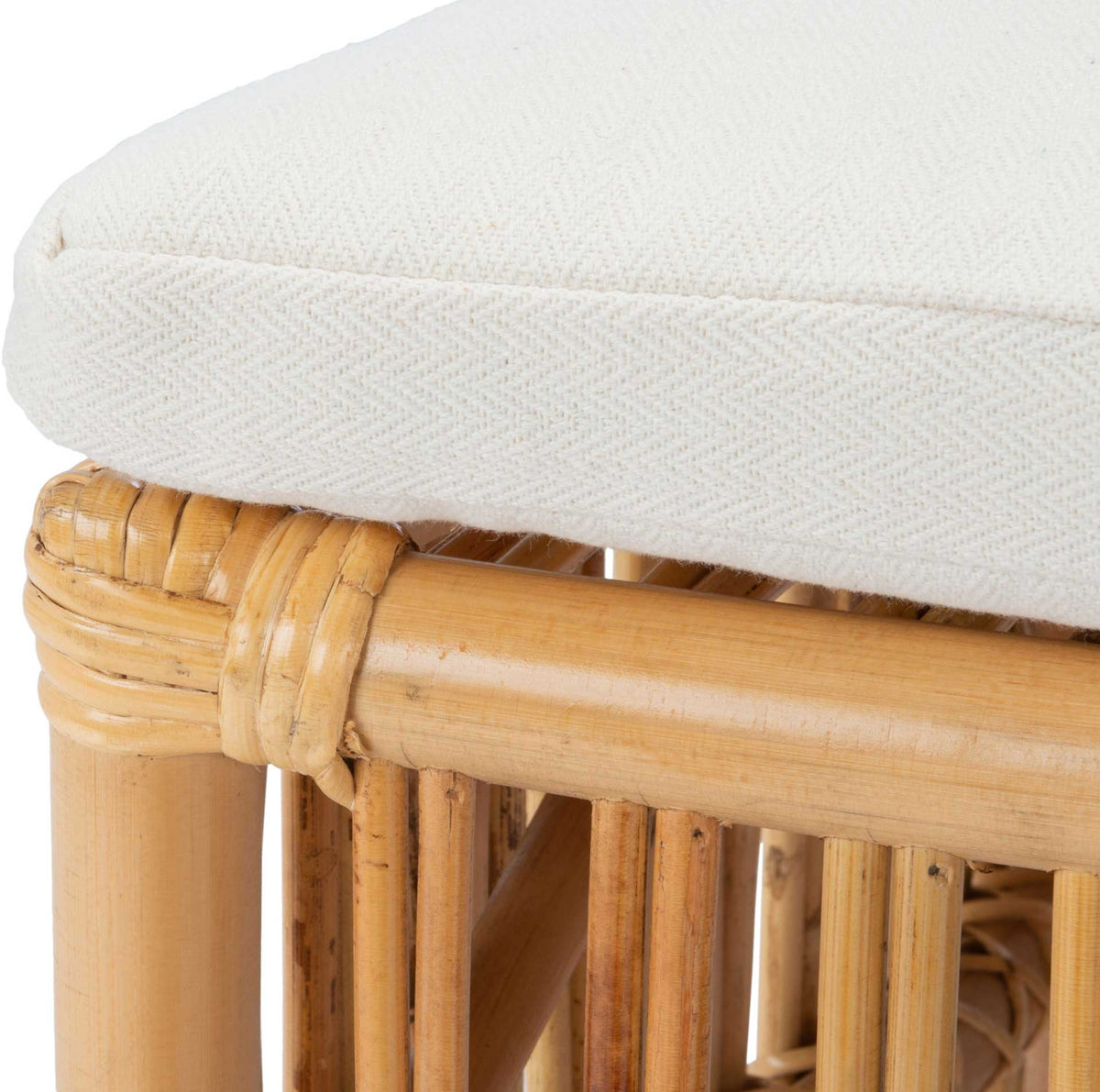 A thick white cushion with subtle woven texture rests atop a wrapped rattan frame