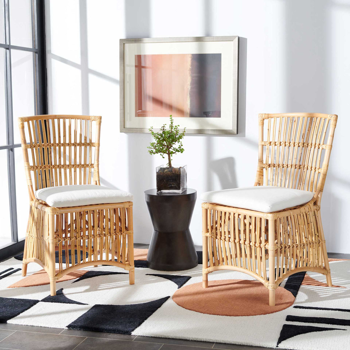 A pair of natural rattan chairs with white cushions brings warmth to a relaxed space