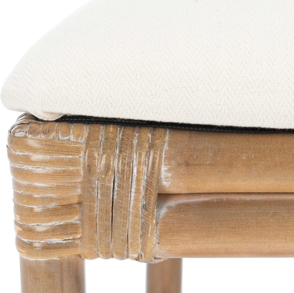 Soft white cushion rests on a whitewashed rattan frame with tightly wrapped corner joints