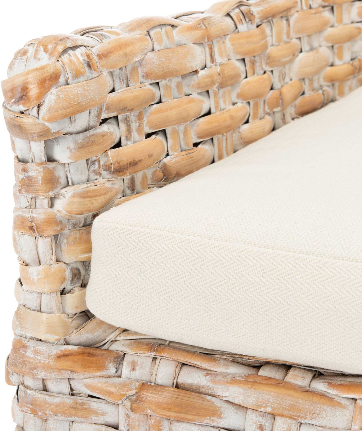 A soft white cushion meets the textured whitewashed rattan arm and woven seat frame