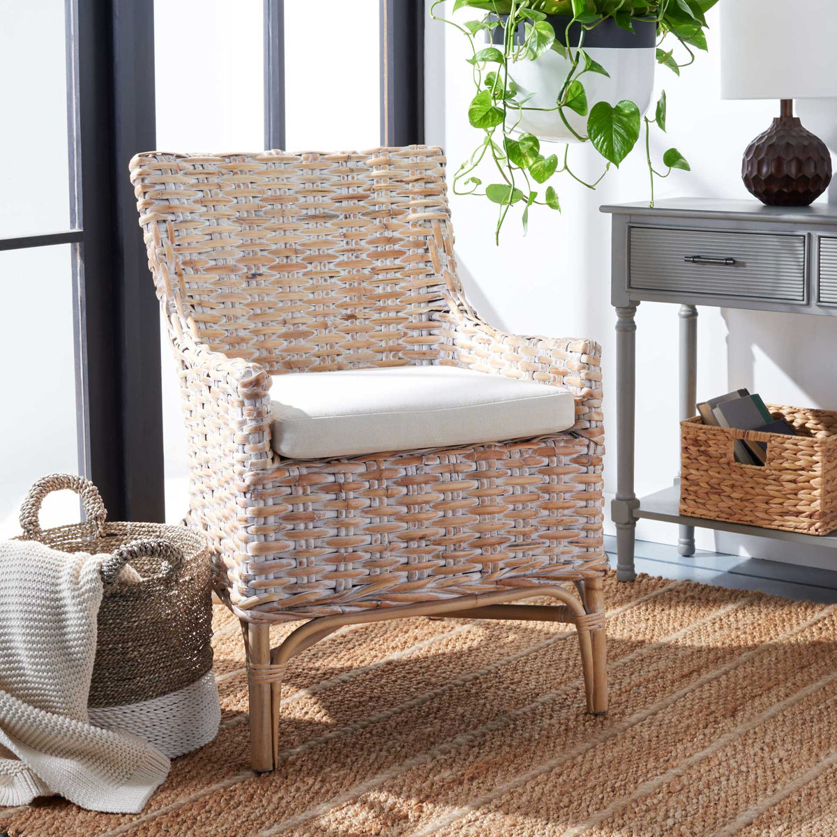 A whitewashed rattan chair and soft white cushion bring coastal texture to a sunlit living space