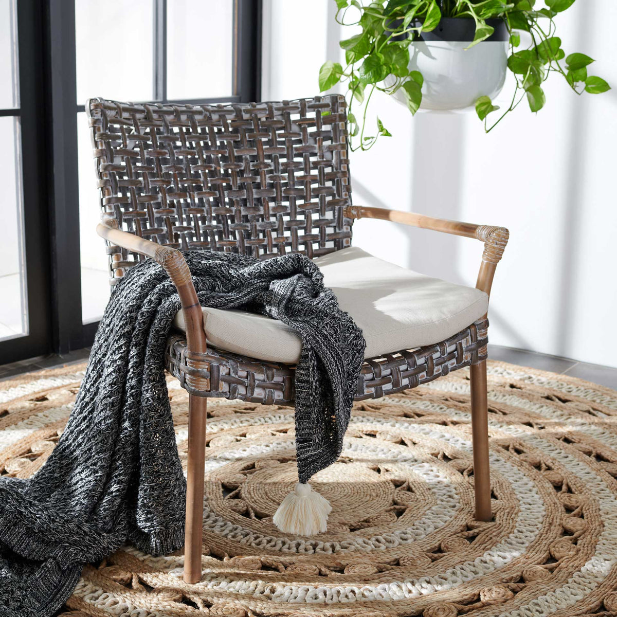 A gray-washed woven rattan chair with a white cushion brings relaxed coastal texture to a bright space.
