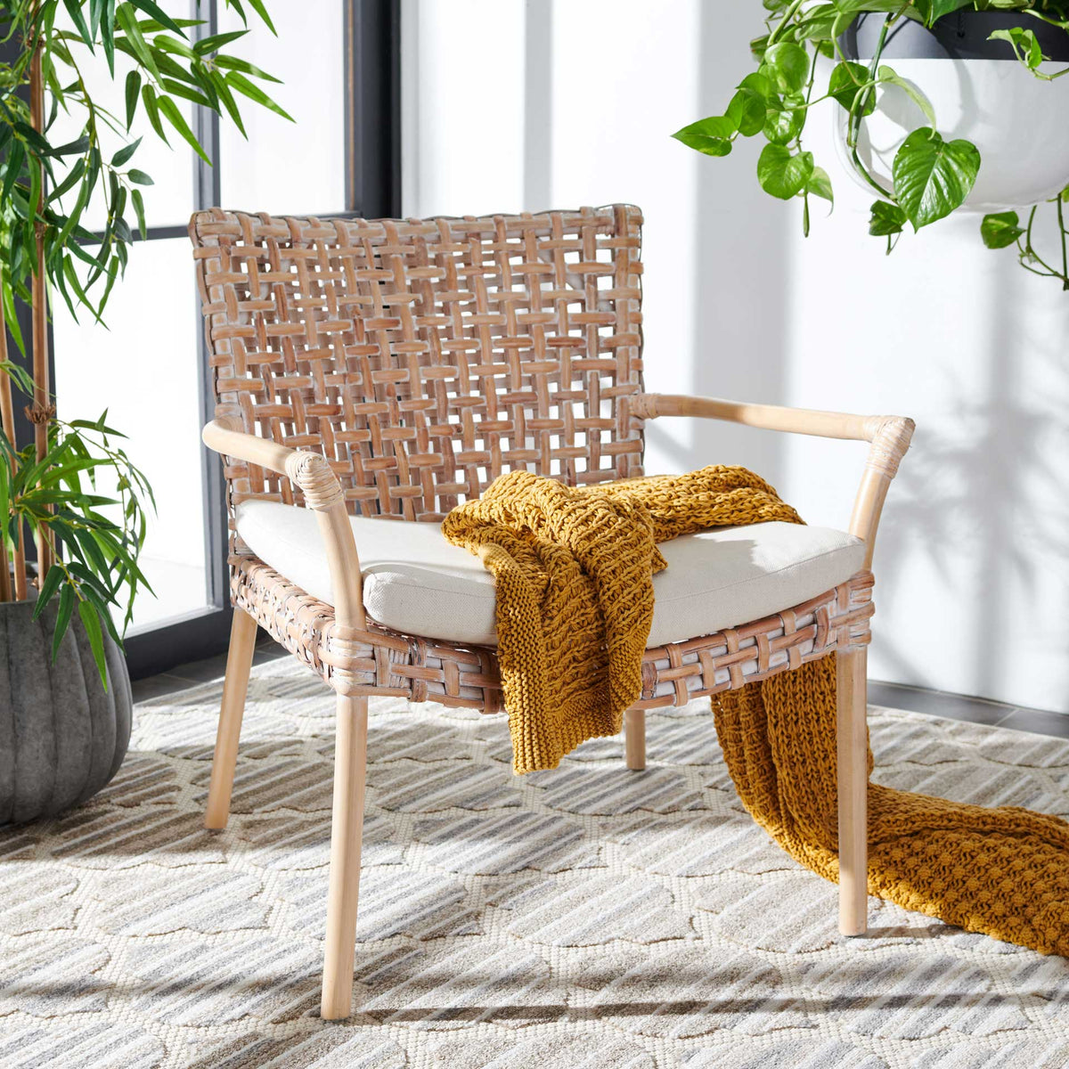 A pale rattan chair with a white cushioned seat adds light, woven texture to a sunlit space.