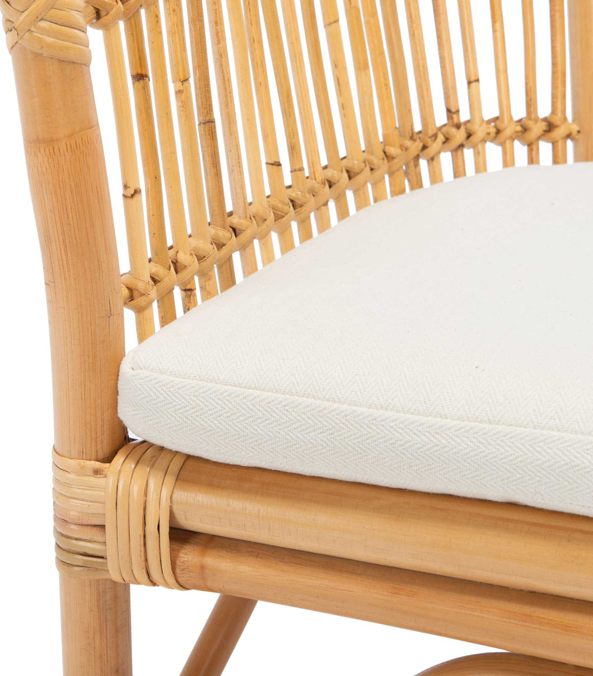 A textured white seat cushion meets natural rattan spindles and a wrapped frame.