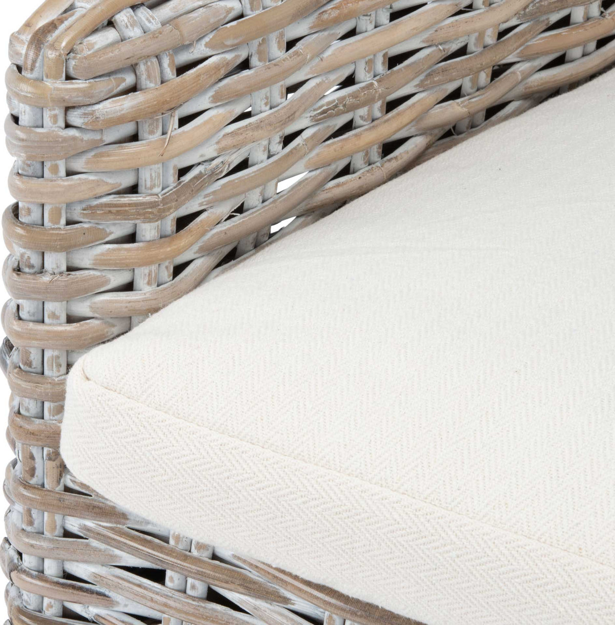 A textured white seat cushion nestles against the gray-whitewashed rattan frame.