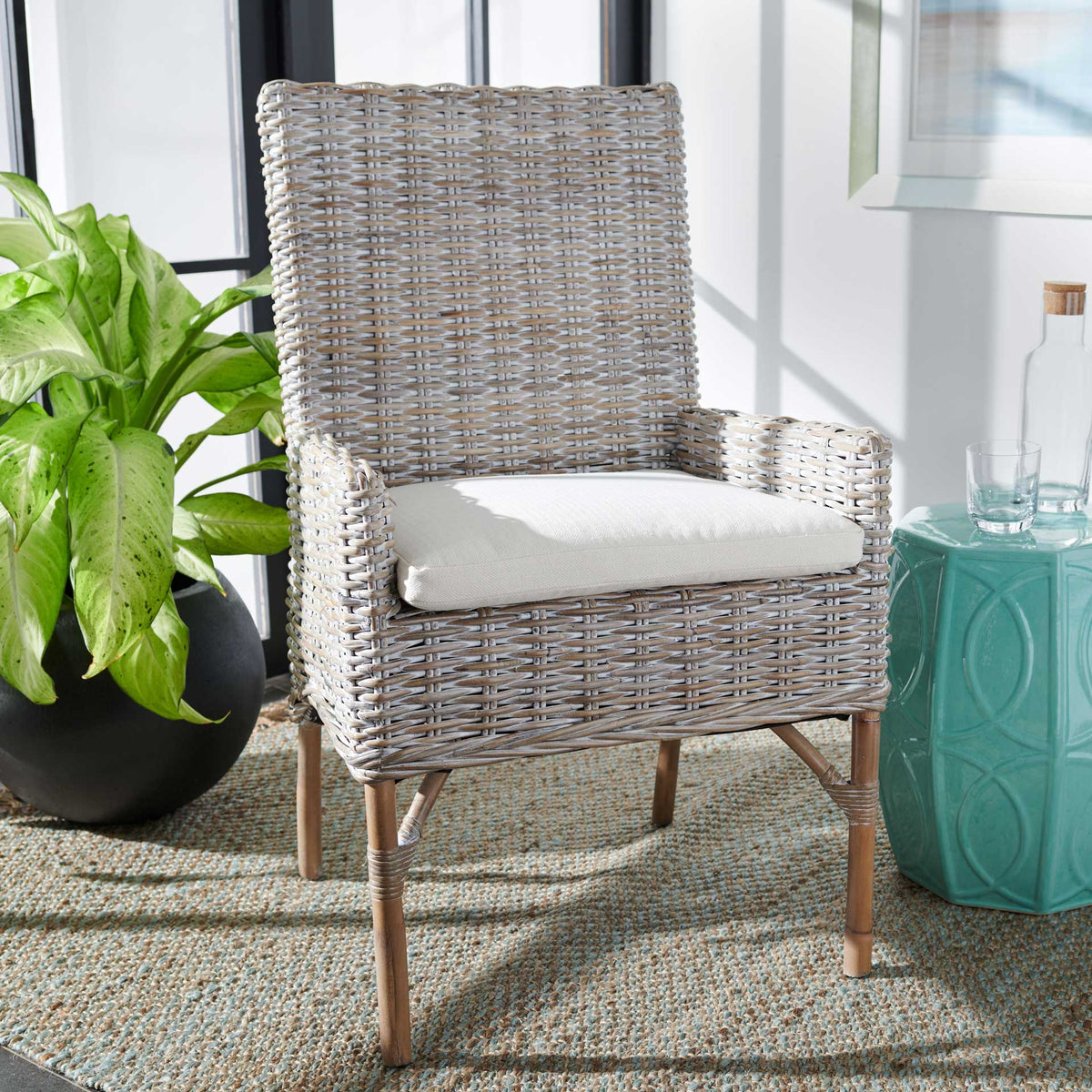 A gray-whitewashed rattan chair brings breezy woven texture and white-cushioned comfort to a living space.