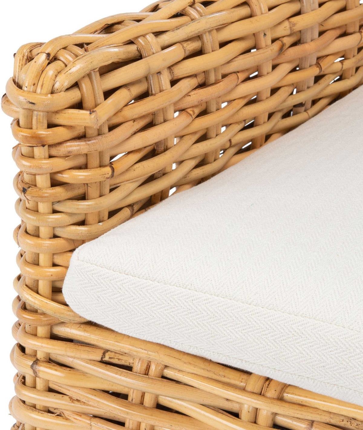 The white cushion's textured trim meets warm natural rattan weaving along the chair arm.