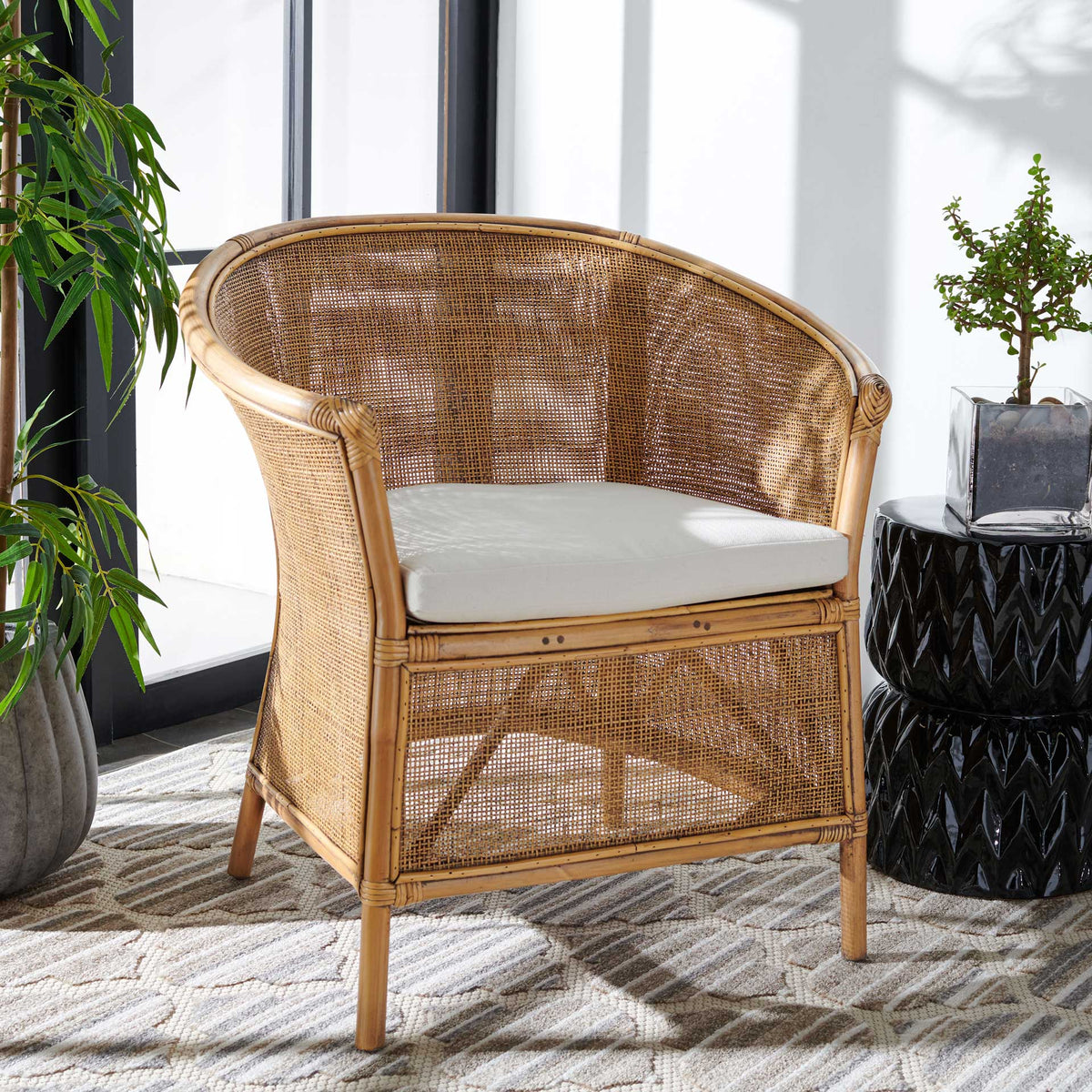 Curved rattan arms, an open woven back, and a white cushion bring coastal warmth to the chair