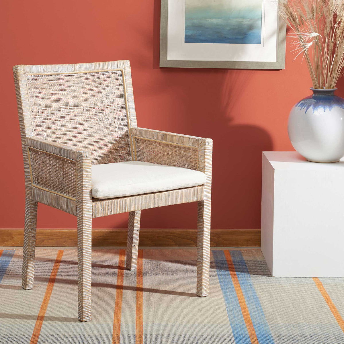 A white seat cushion and gray-whitewashed cane arms lend the chair breezy coastal charm.
