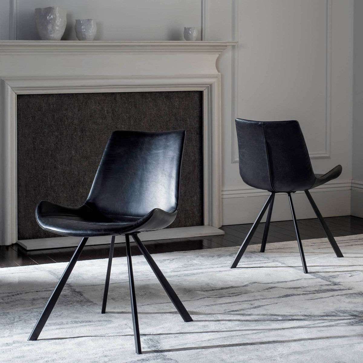 Two black dining chairs lend sleek silhouettes and slender legs to a contemporary living room