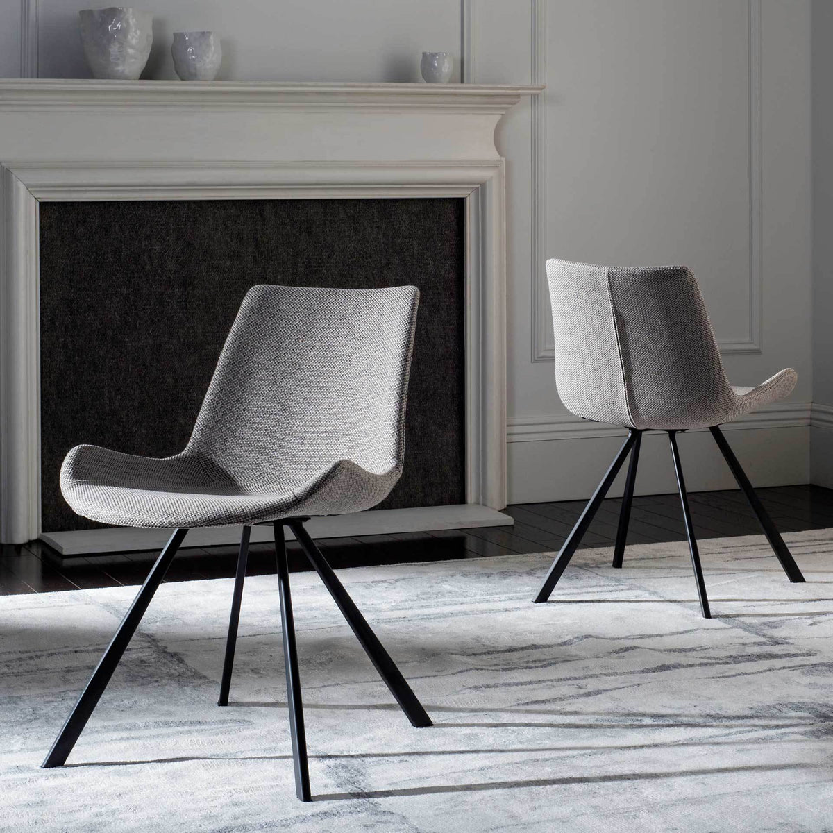 Two light gray chairs bring sculpted seats and airy black legs to a modern living room