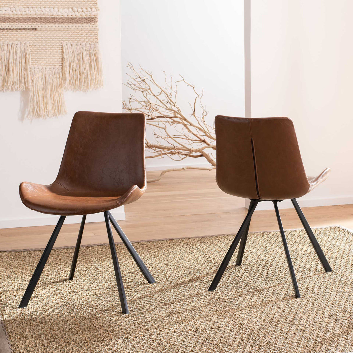 Two brown chairs bring softly contoured seats and airy black legs to a bright living area