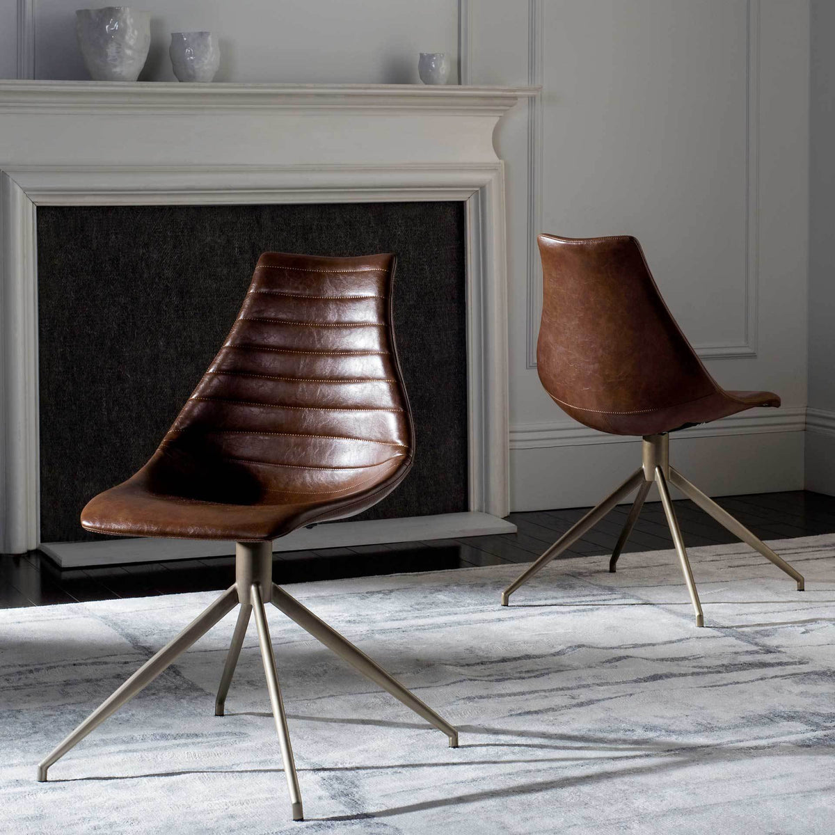 Two brown faux leather swivel chairs bring stitched texture and slim brass-tone legs to a living space