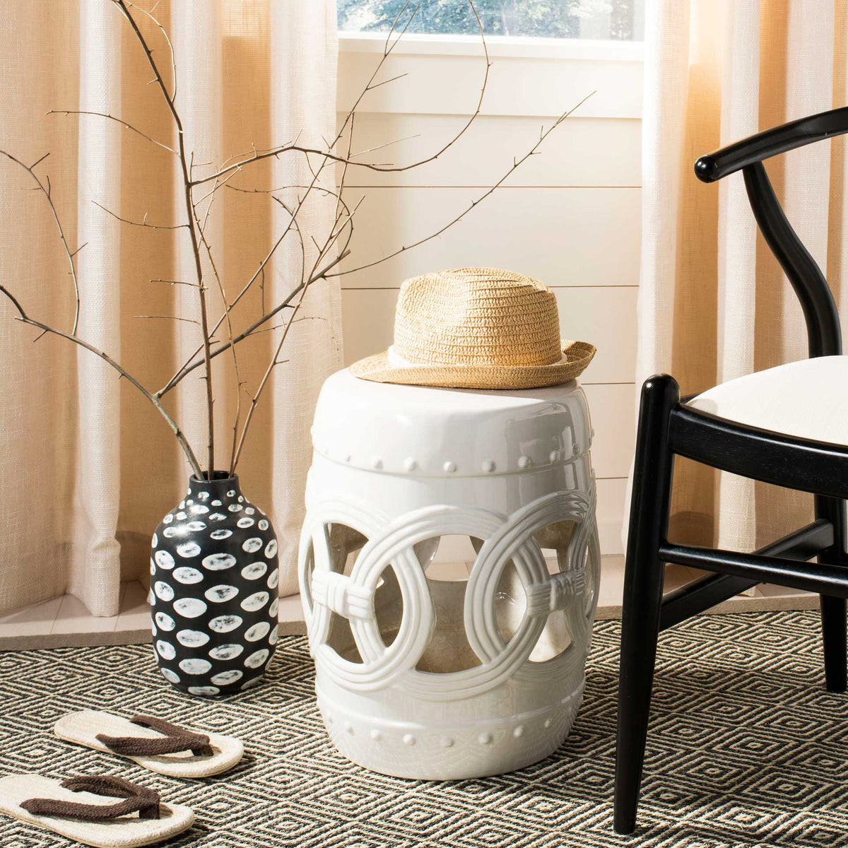 White ceramic garden stool with open coinwork serves as a handy accent beside a chair