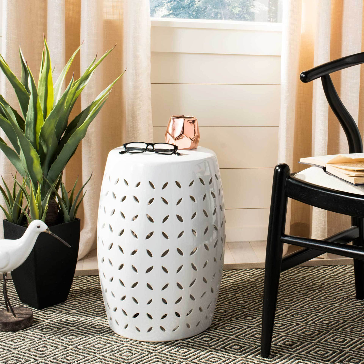 White petal-cutout garden stool provides a handy side table beside a chair