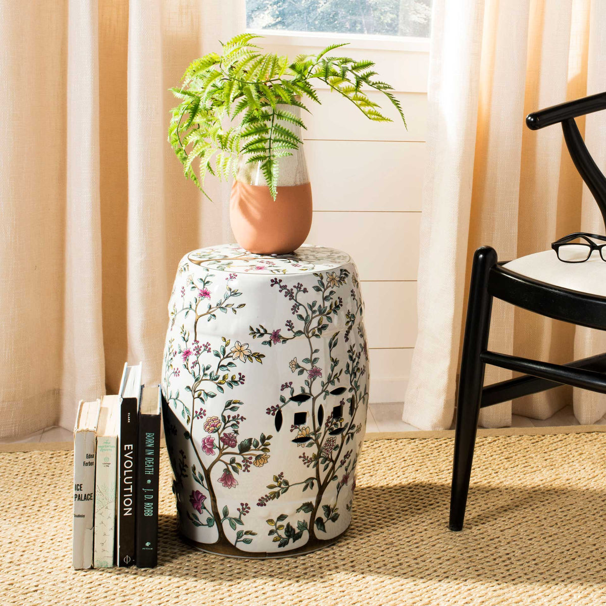 A floral ceramic garden stool provides a colorful perch for a potted fern