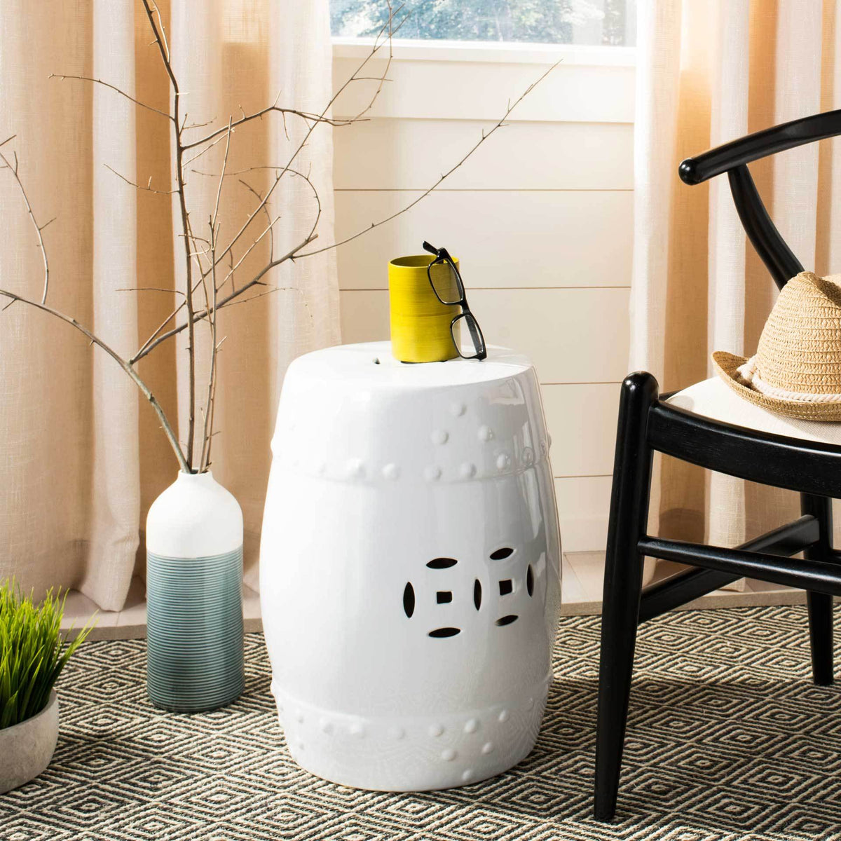 White garden stool doubles as a compact table, with a pierced design and delicate dot accents.