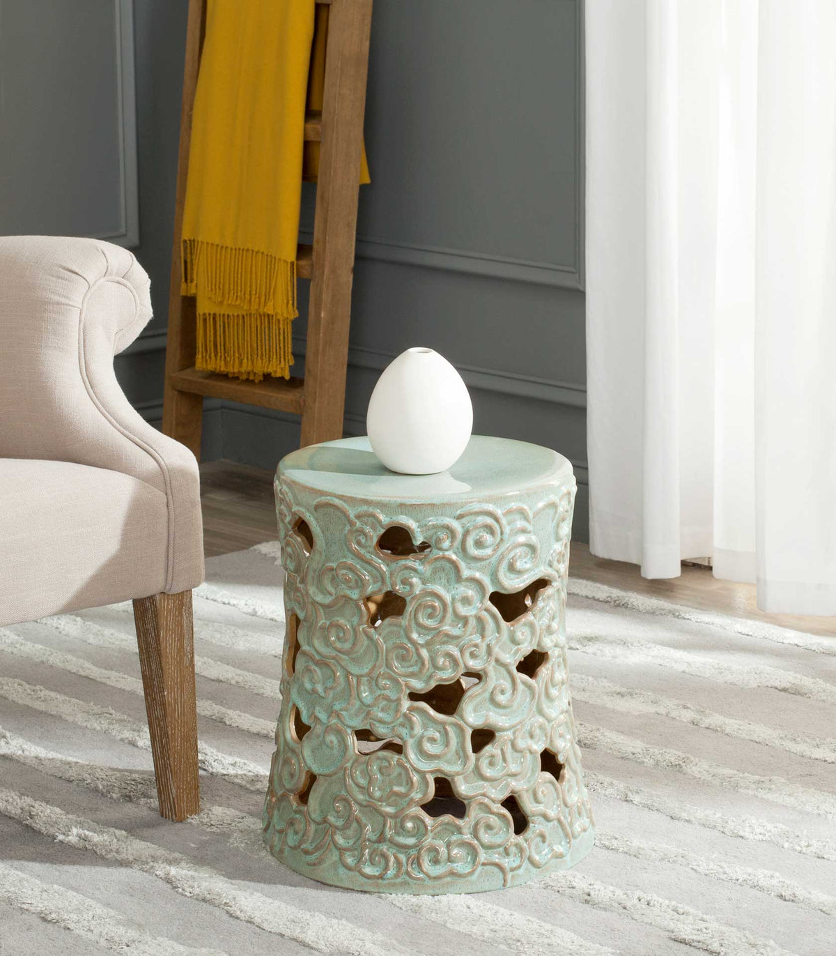 Light green openwork ceramic stool serves as a side table beside an armchair