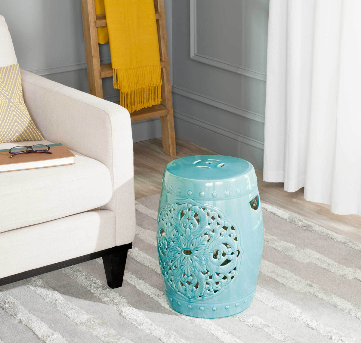 A smooth rounded top and floral openwork give this blue ceramic stool sculptural appeal.