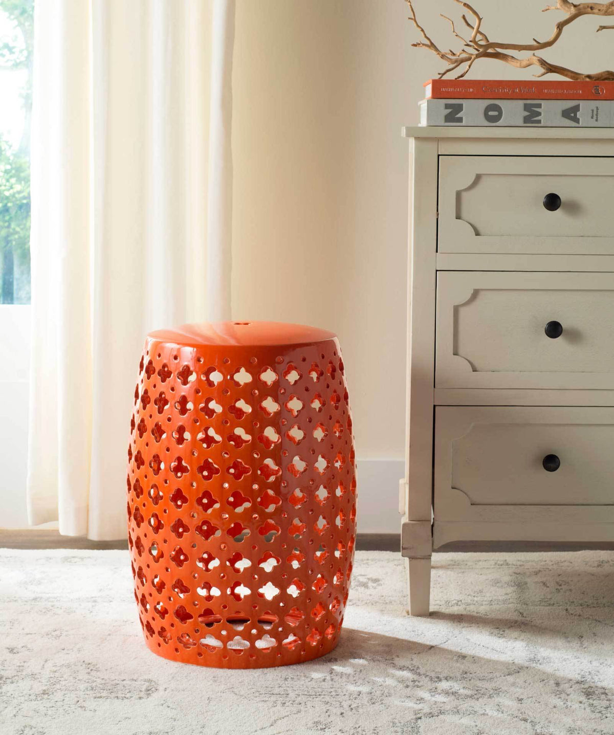 Bright orange ceramic garden stool brings bold color and an airy cutout pattern to a living space