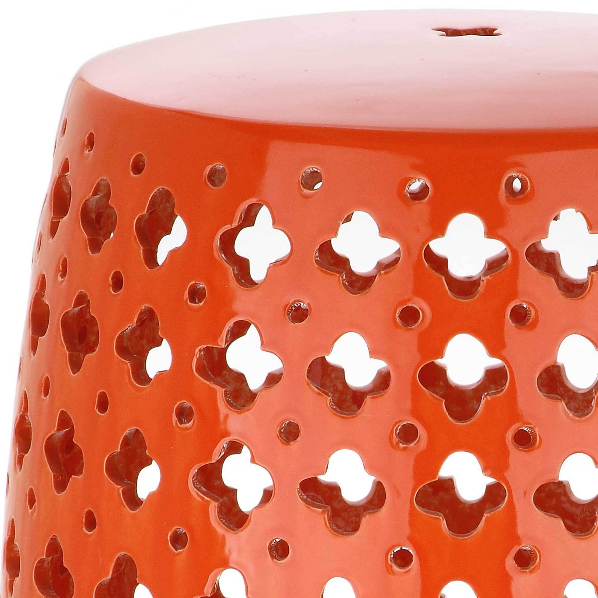 Glossy orange glaze surrounds clover-shaped openings and small round perforations