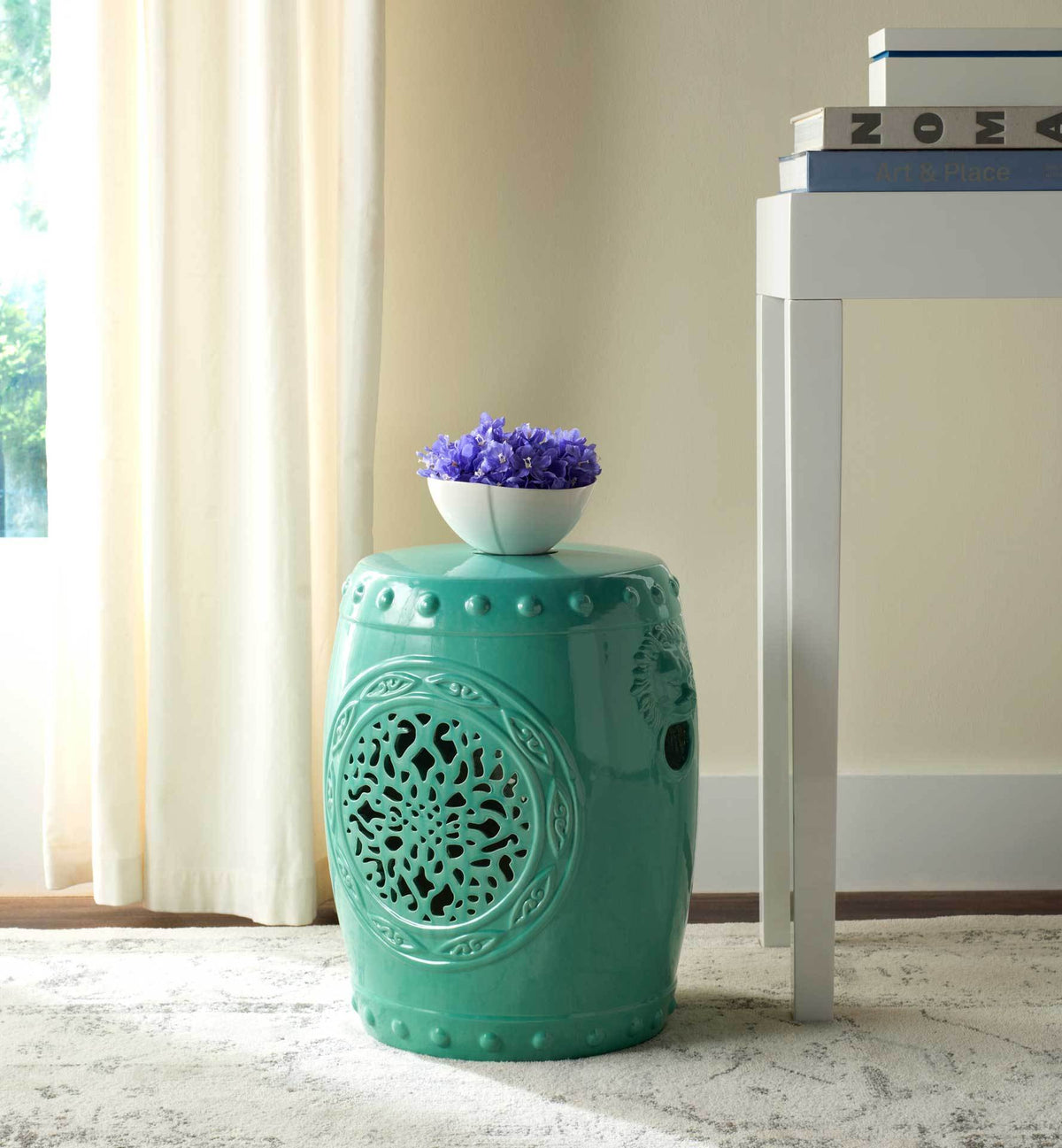 Aqua ceramic garden stool serves as a colorful side table for a bowl of flowers