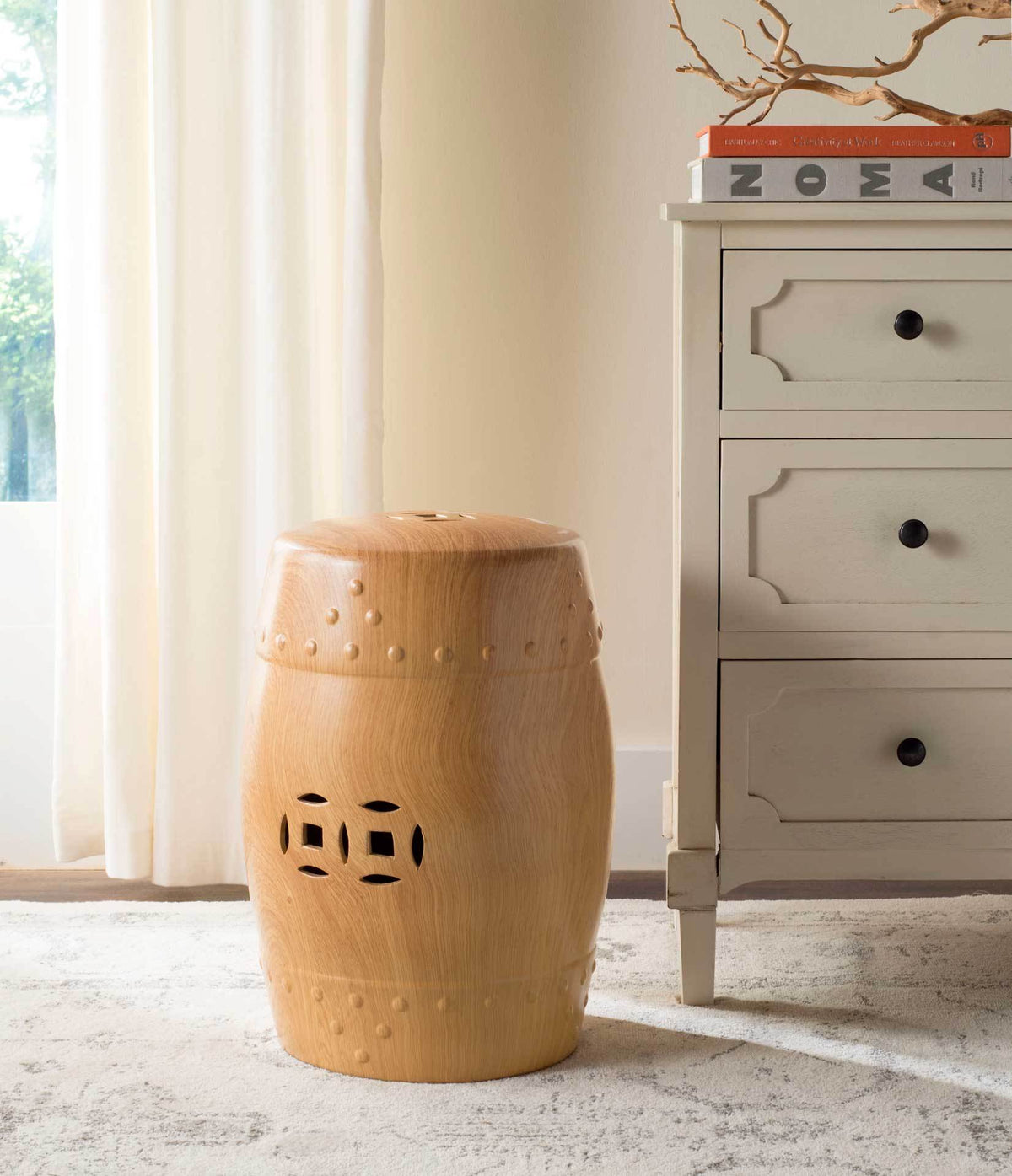 A warm golden ceramic stool brings wood-grain texture and intricate cutouts beside a dresser.