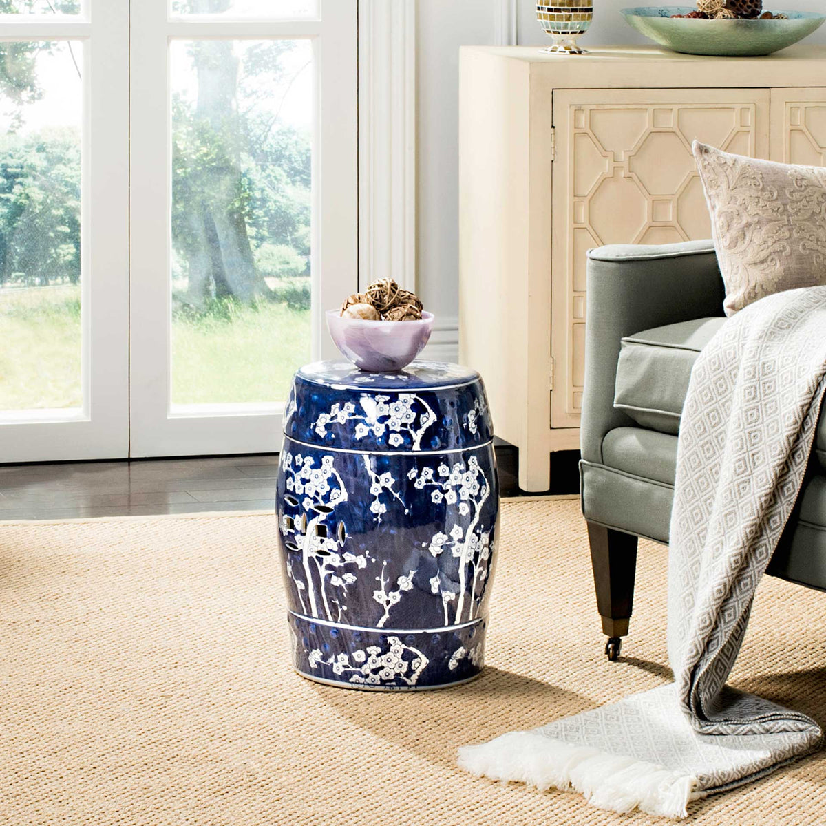 Blossom-patterned ceramic garden stool serves as a side table beside an upholstered chair
