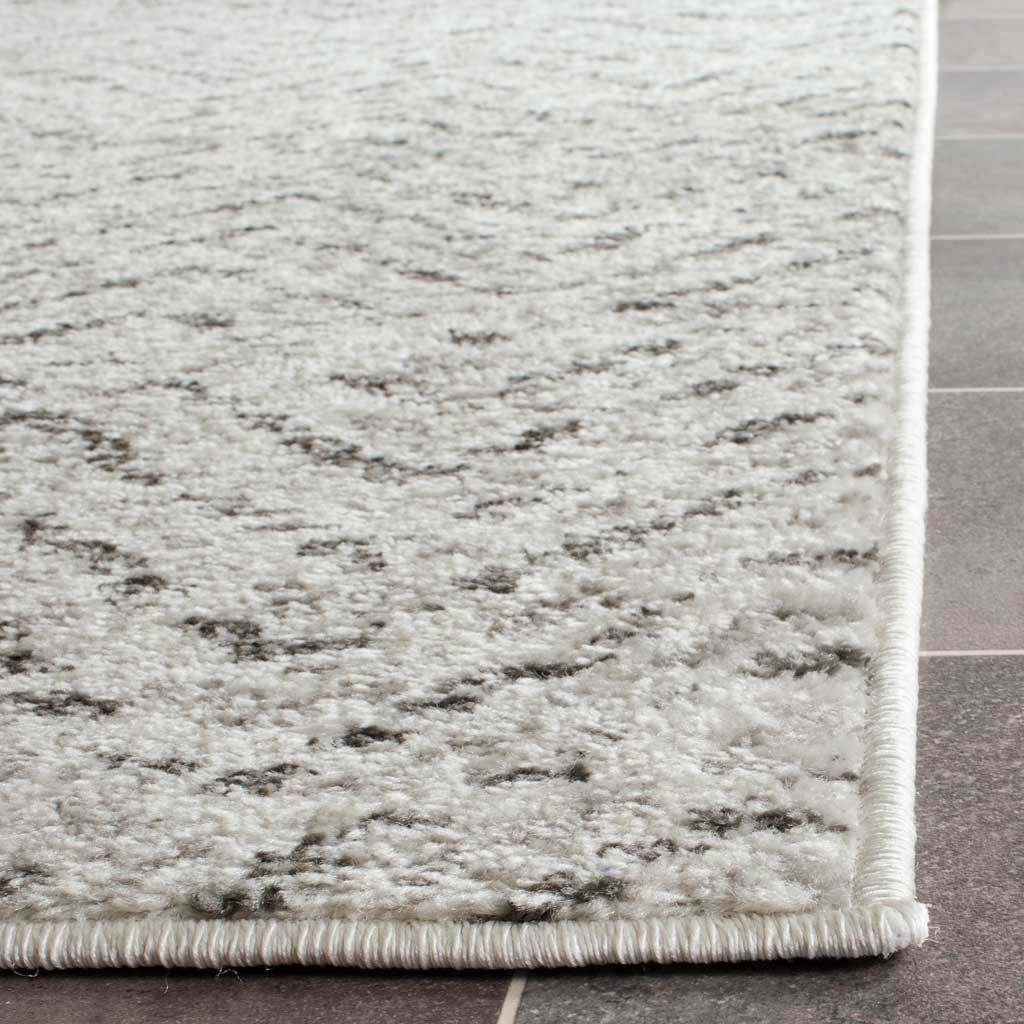 Neatly bound edges frame textured ivory pile with charcoal accents