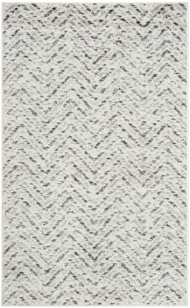 Charcoal chevrons scatter across an ivory rug with a softly worn finish